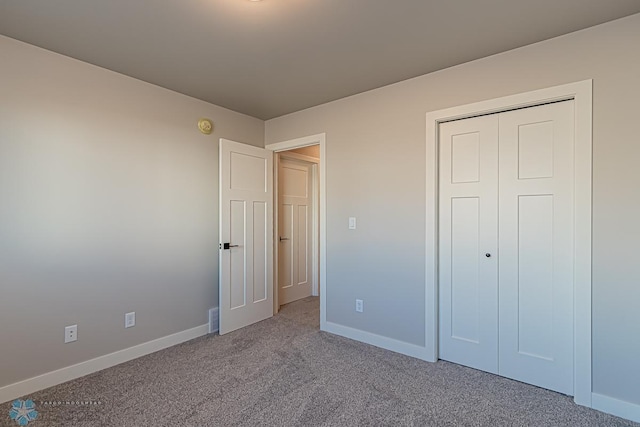 unfurnished bedroom featuring light colored carpet and a closet