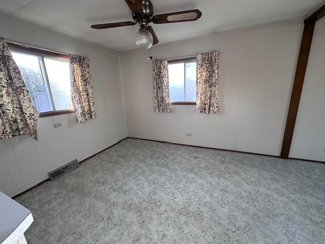 carpeted empty room with ceiling fan and plenty of natural light