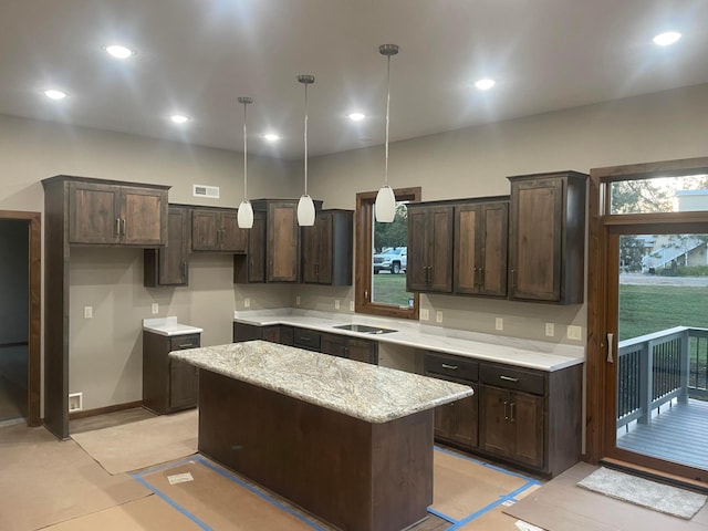 kitchen with pendant lighting, dark brown cabinetry, light stone countertops, and a kitchen island