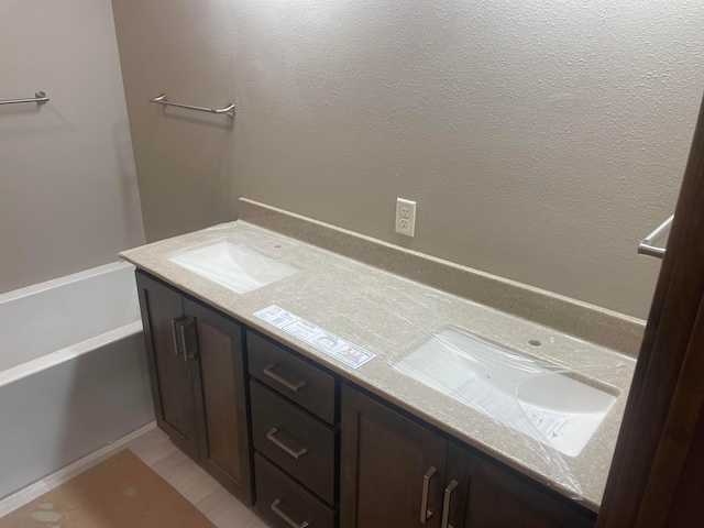 bathroom with tile patterned floors, a bathing tub, and vanity