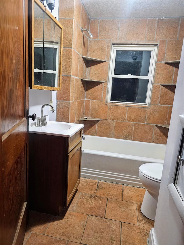 full bathroom with a textured ceiling, vanity, toilet, and tiled shower / bath