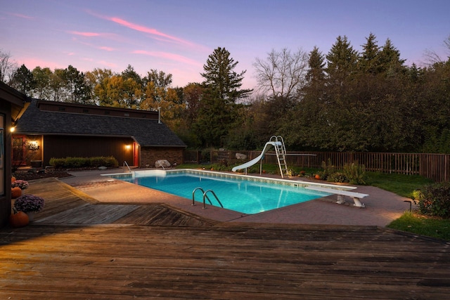 6517 Crackleberry Trl, Woodbury, MN 55129 - pool at dusk with a deck, a fenced backyard, a water slide, and a diving board