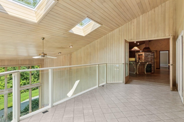 6517 Crackleberry Trl, Woodbury, MN 55129 - tiled empty room with a skylight, vaulted ceiling, a ceiling fan, and wood walls