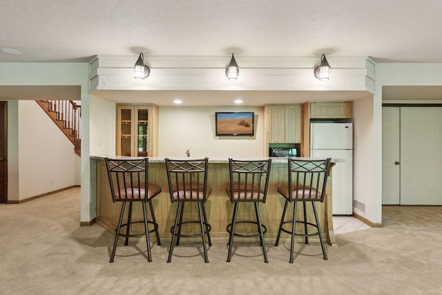 6517 Crackleberry Trl, Woodbury, MN 55129 - kitchen featuring freestanding refrigerator, light colored carpet, a breakfast bar, and a peninsula