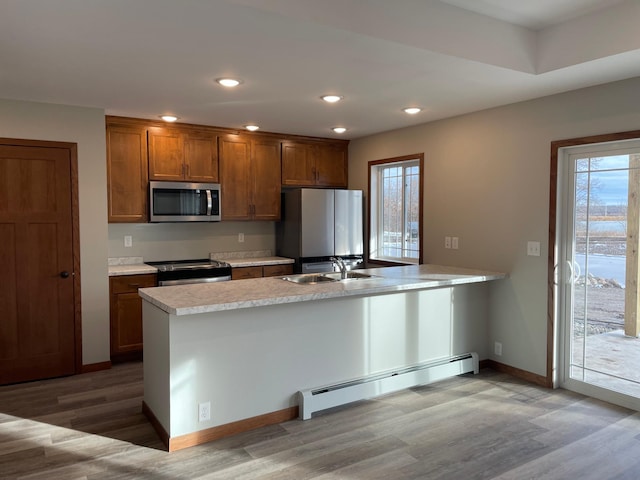 kitchen featuring wood-type flooring, sink, appliances with stainless steel finishes, and a baseboard radiator