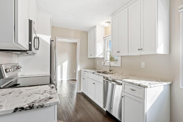 kitchen with light stone counters, dark wood-style floors, a sink, white cabinets, and appliances with stainless steel finishes