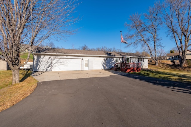 ranch-style house featuring a garage, a wooden deck, and a front lawn