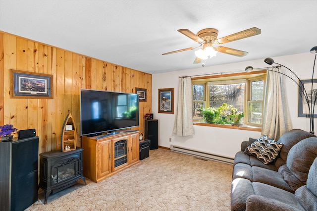 carpeted living room featuring ceiling fan, wood walls, and a baseboard heating unit