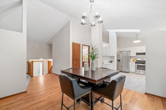 dining area featuring a chandelier, high vaulted ceiling, and light hardwood / wood-style flooring