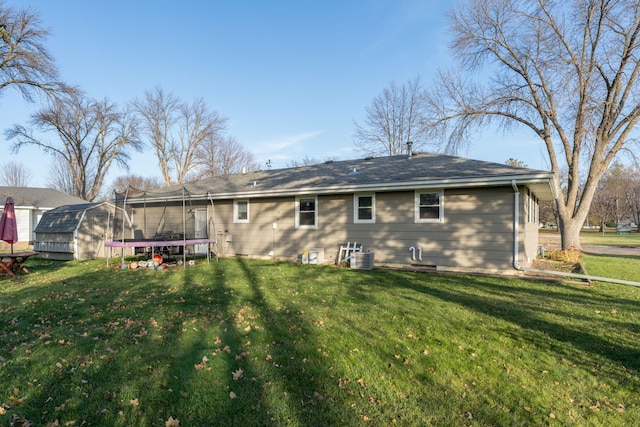 back of property featuring a yard, central AC unit, and a trampoline