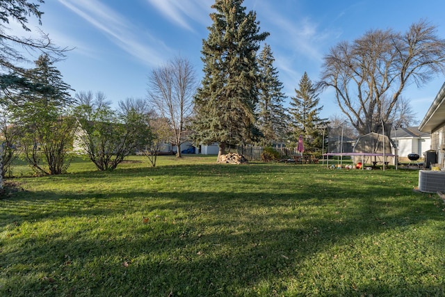 view of yard featuring central AC unit and a trampoline