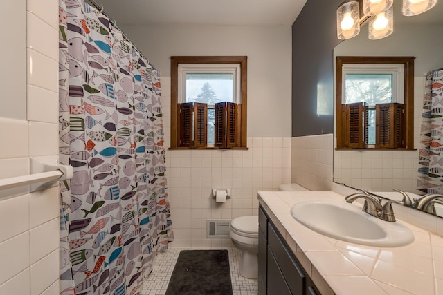 bathroom featuring tile patterned flooring, a wealth of natural light, tile walls, and toilet