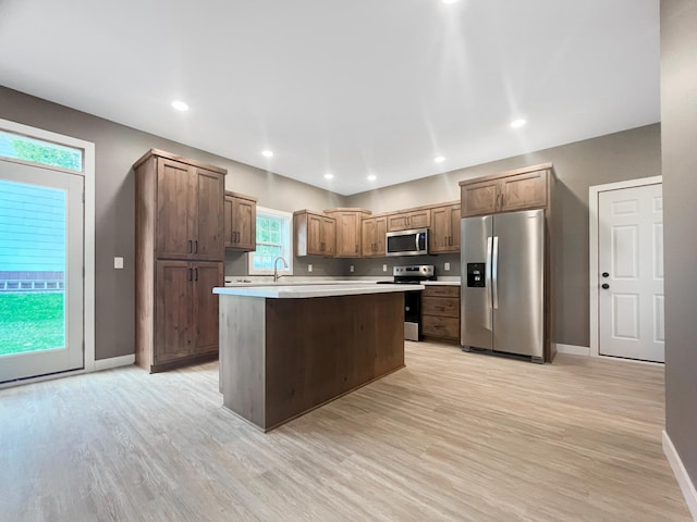 kitchen with appliances with stainless steel finishes, light hardwood / wood-style floors, a kitchen island, and sink