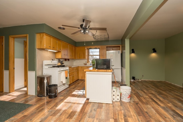 kitchen with ceiling fan, white appliances, hardwood / wood-style floors, and a kitchen island