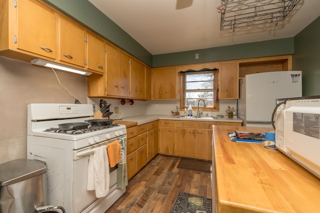 kitchen with sink, white appliances, and dark hardwood / wood-style floors