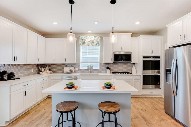 kitchen featuring stainless steel appliances, white cabinetry, light hardwood / wood-style flooring, and a kitchen island