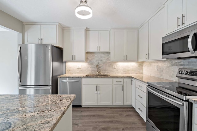 kitchen featuring white cabinets, stainless steel appliances, sink, and light stone counters