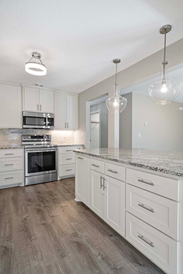 kitchen with white cabinets, appliances with stainless steel finishes, dark wood-type flooring, and decorative light fixtures