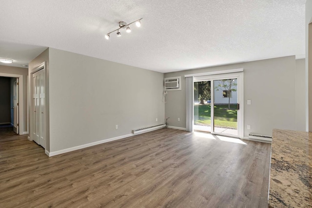 unfurnished room with hardwood / wood-style floors, a baseboard radiator, a textured ceiling, and a wall mounted air conditioner