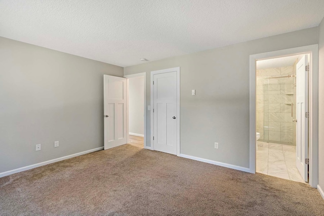 unfurnished bedroom featuring a textured ceiling, light carpet, and ensuite bath