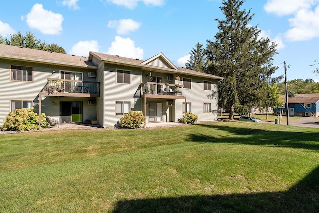 back of property with a lawn and a balcony