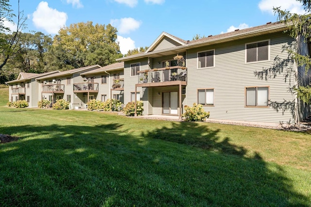 rear view of house featuring a lawn and a balcony