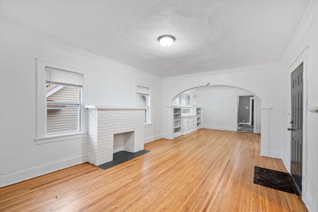 unfurnished living room featuring a fireplace, hardwood / wood-style floors, a textured ceiling, and ornamental molding