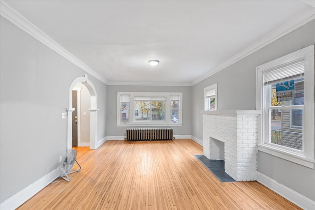 unfurnished living room with radiator heating unit, ornamental molding, a healthy amount of sunlight, and light hardwood / wood-style floors