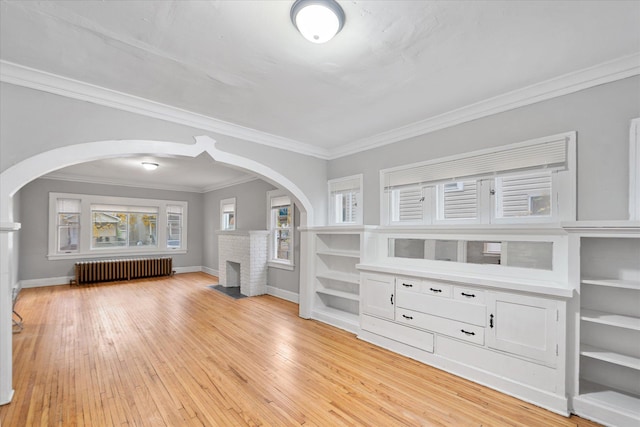 unfurnished living room featuring ornamental molding, a brick fireplace, light hardwood / wood-style floors, and radiator