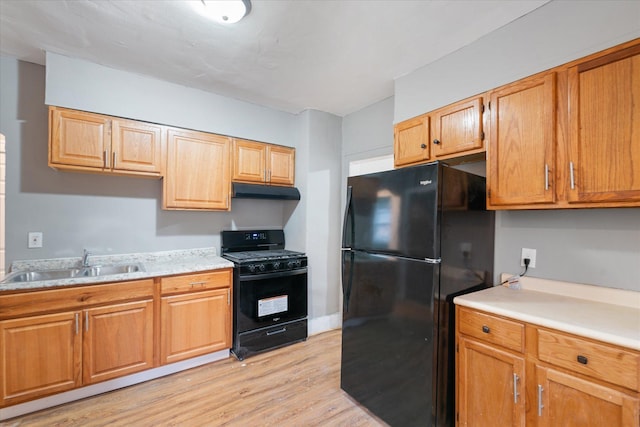 kitchen featuring black appliances, sink, and light wood-type flooring