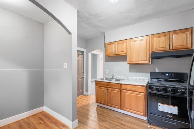 kitchen featuring gas stove, light stone countertops, sink, and light hardwood / wood-style floors