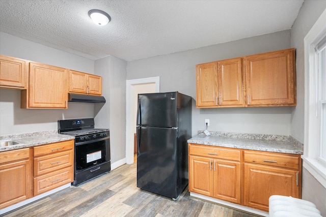 kitchen with radiator heating unit, black appliances, a textured ceiling, and light wood-type flooring