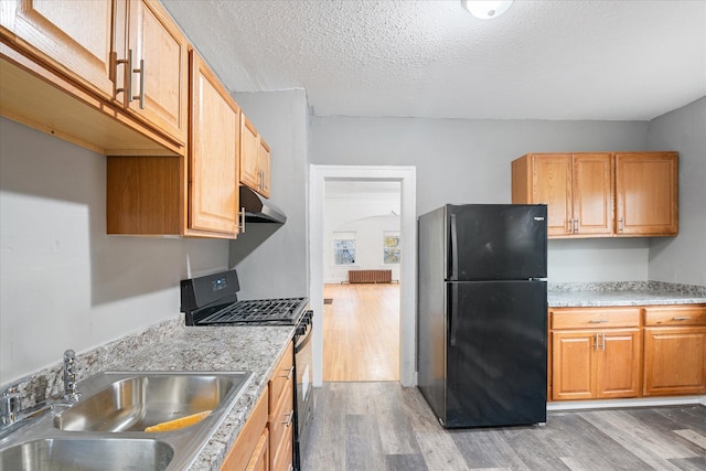 kitchen with black appliances, hardwood / wood-style floors, sink, and a textured ceiling