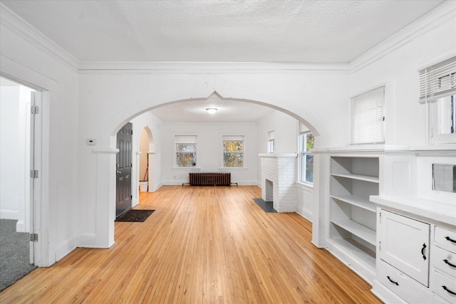 interior space featuring radiator heating unit, a textured ceiling, light hardwood / wood-style floors, and crown molding