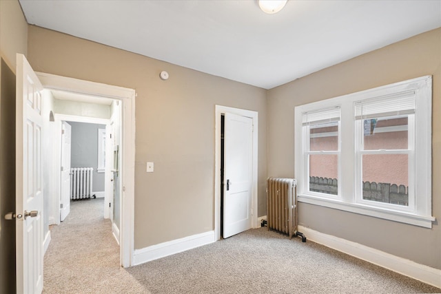 unfurnished bedroom featuring radiator heating unit and light colored carpet