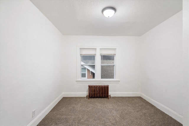 carpeted empty room featuring a textured ceiling and radiator