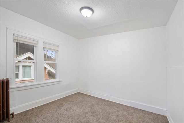 carpeted empty room featuring radiator heating unit and a textured ceiling