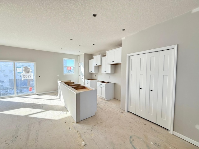 kitchen featuring white cabinetry, a center island, and a textured ceiling