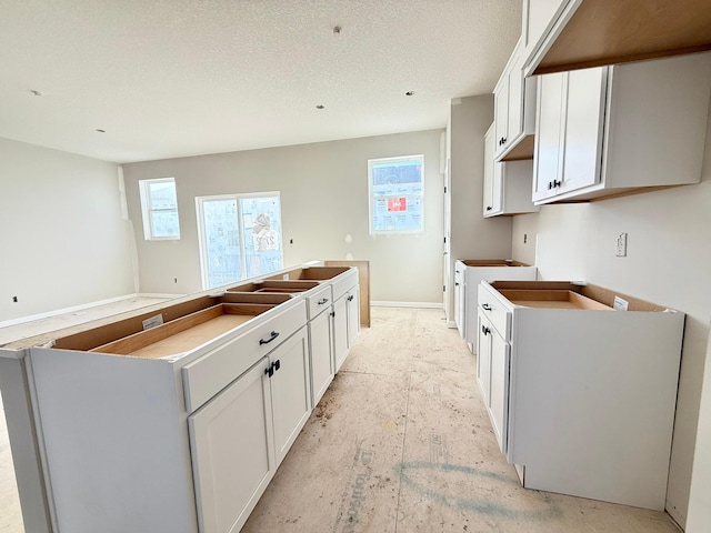 kitchen with a kitchen island, white cabinets, and a textured ceiling