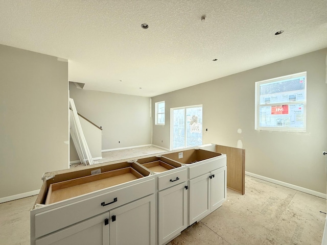 kitchen featuring a center island, a textured ceiling, and white cabinets