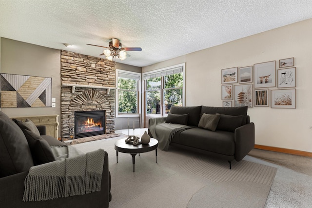 living room featuring ceiling fan, a fireplace, and a textured ceiling