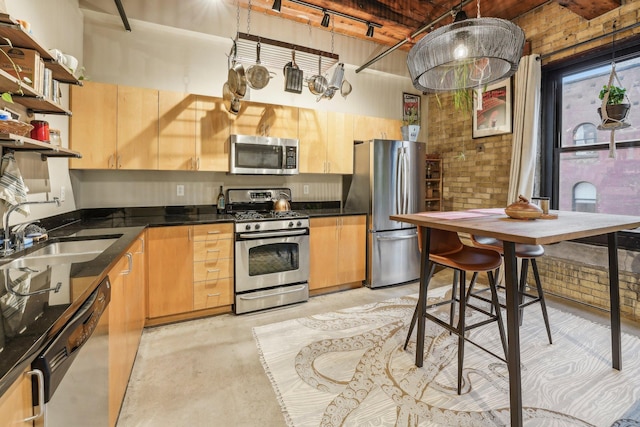 kitchen with appliances with stainless steel finishes, sink, decorative light fixtures, and brick wall