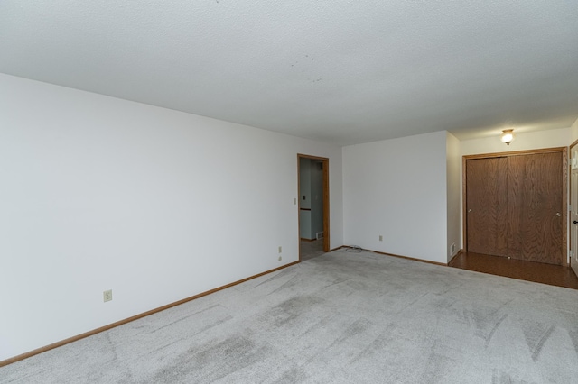 unfurnished room featuring a textured ceiling and light carpet