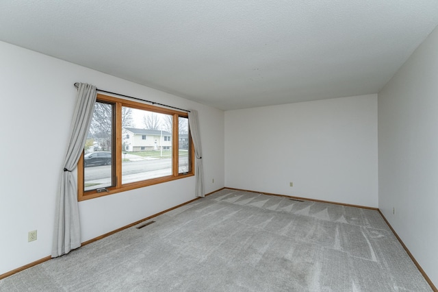 empty room with light colored carpet and a textured ceiling