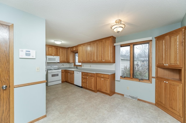 kitchen with a textured ceiling, sink, and white appliances