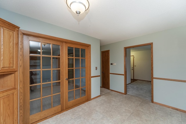 empty room featuring a textured ceiling and french doors