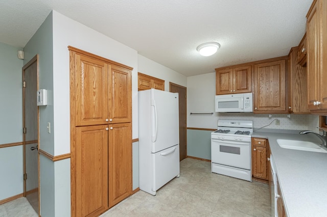 kitchen featuring a textured ceiling, sink, and white appliances