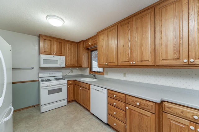 kitchen with sink, white appliances, and a textured ceiling