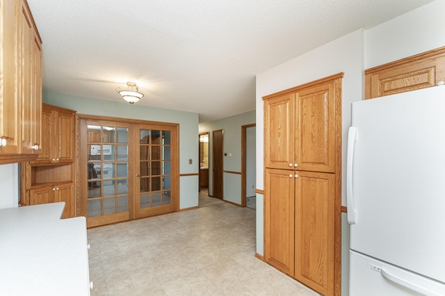 kitchen featuring french doors, white fridge, and a textured ceiling