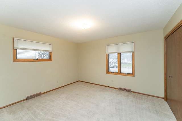 spare room featuring light carpet and a textured ceiling